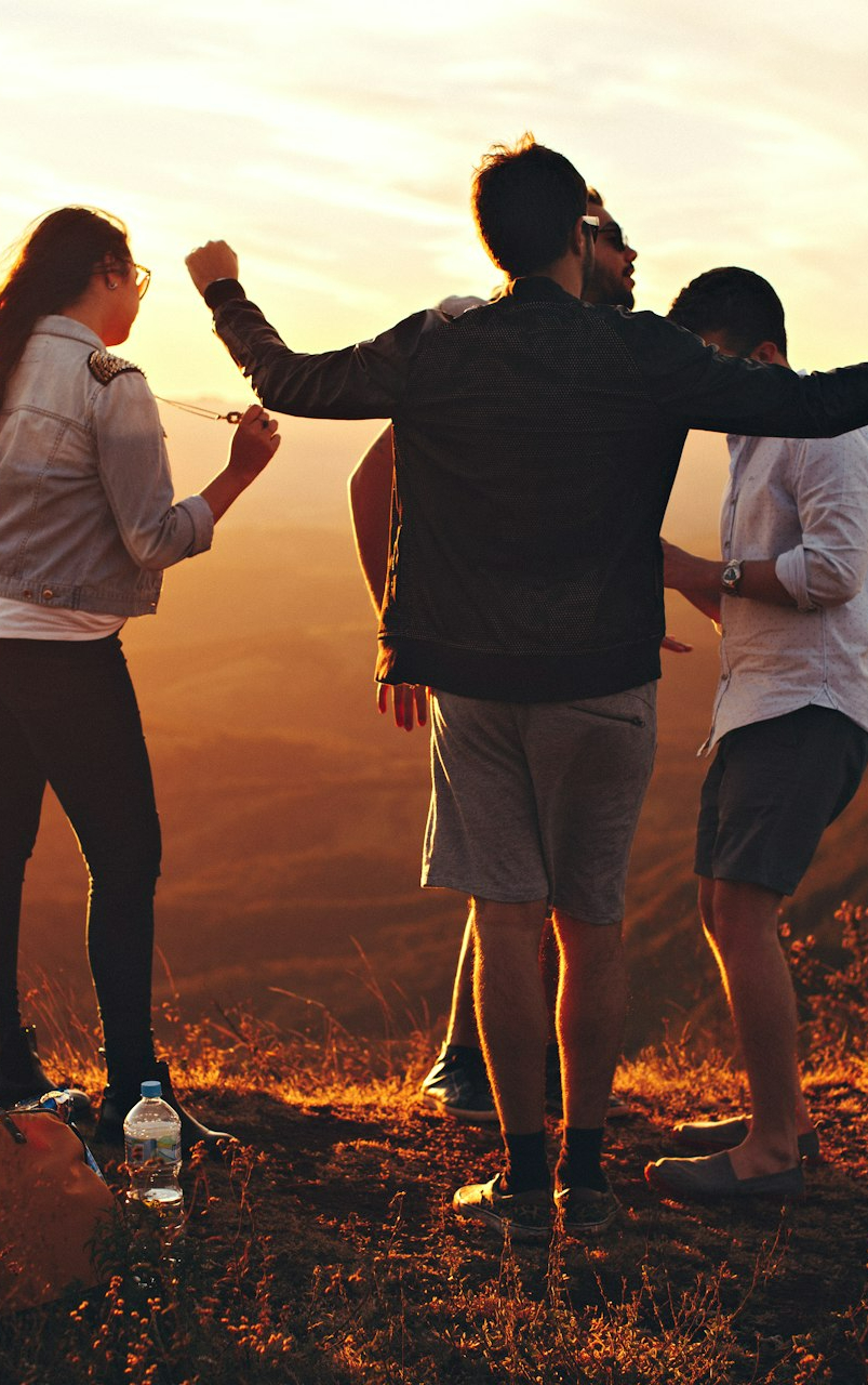 four people standing on edge of mountain