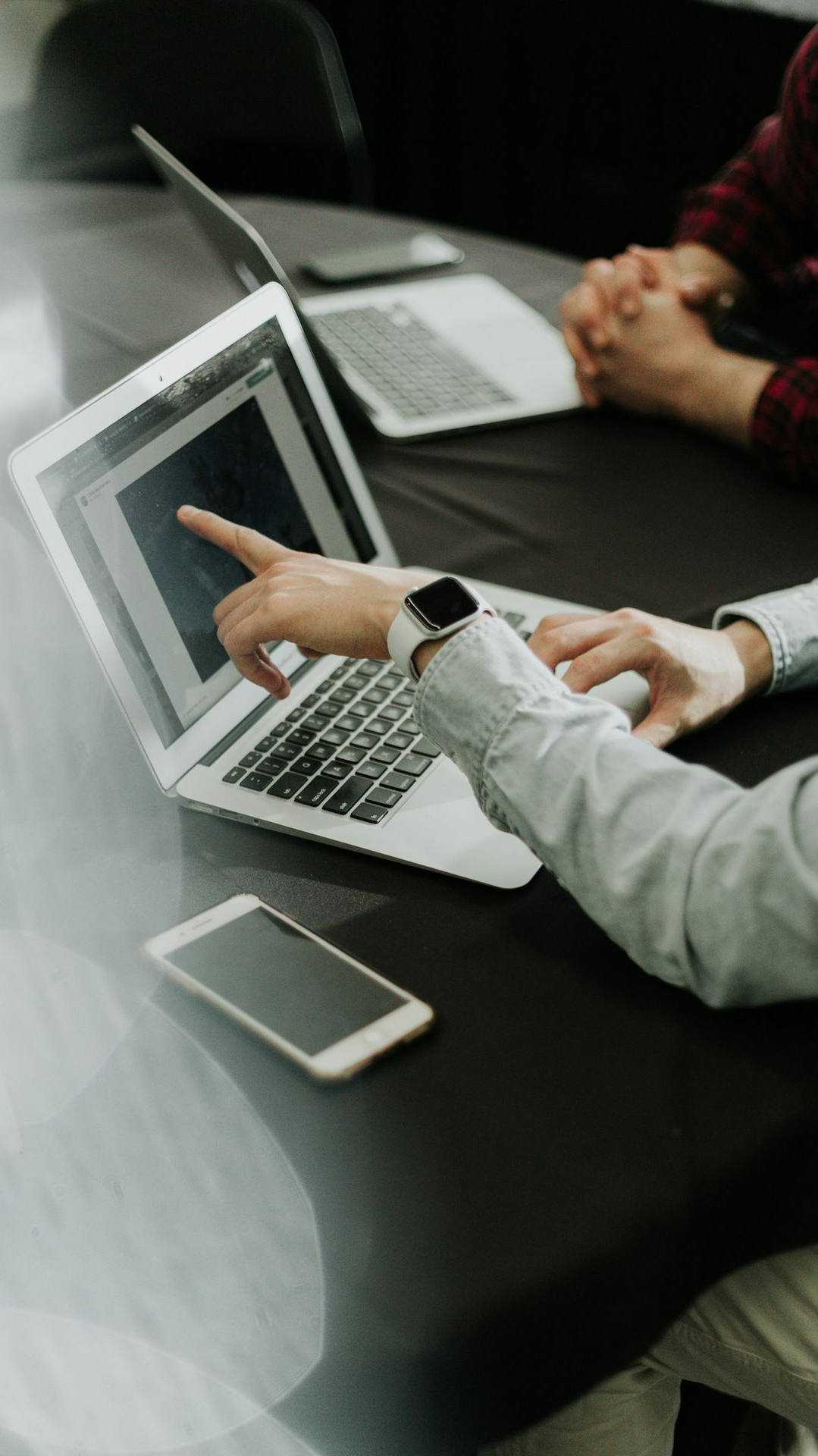 two people sitting at a table with laptops